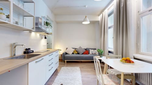 Modern studio apartment at tARTu Stays with open kitchen, dining area, and gray sofa in Tartu city center