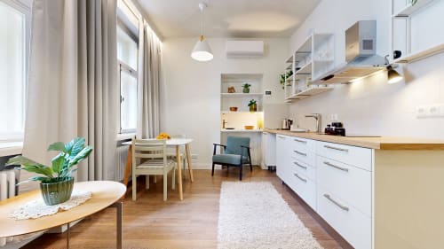 Modern kitchen and dining area in tARTu Stays apartment with white cabinets, wooden counters, and city view in Tartu