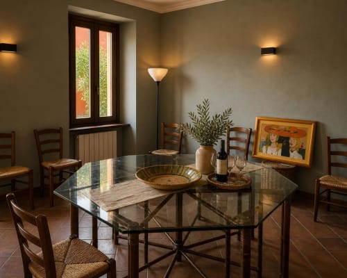 Elegante sala da pranzo del Grillo.House B&B a Capiago Intimiano con tavolo in vetro, sedie rustiche, bottiglia di vino e atmosfera calda