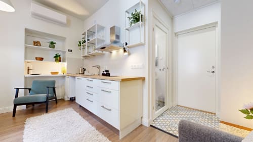 Modern kitchen and living area in tARTu Stays apartment, Tartu, featuring white cabinetry, wooden countertops, and city view