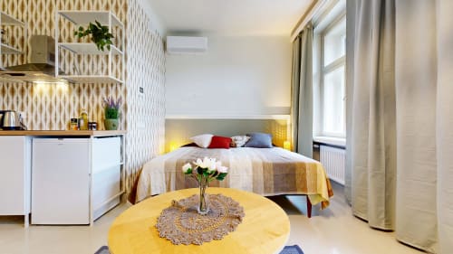 Modern studio apartment at tARTu Stays Tartu with bed, yellow table, kitchenette, and city views