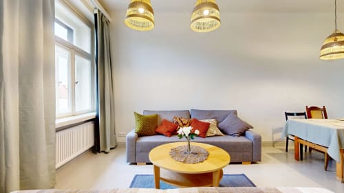 Modern apartment living room at tARTu Stays with gray sofa, yellow table, pendant lights, and city view in Tartu