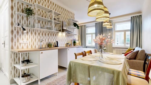Modern kitchen-dining area in tARTu Stays apartment with white cabinetry, gold pendant lights, and city view in Tartu