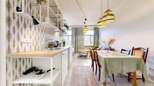 Modern apartment kitchen and dining area at tARTu Stays in Tartu with white cabinetry, brass pendant lights, and city views