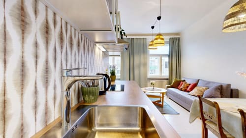 Modern kitchen and living area in tARTu Stays apartment, Tartu, with stainless steel sink, yellow pendant lights, and gray