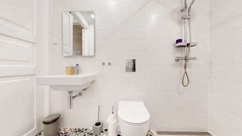 Modern white bathroom with shower, toilet, and sink mirror at tARTu Stays apartment in Tartu city center