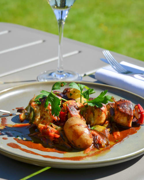 Brochette de viande élégante garnie de légumes à l'Hôtel Des Vosges, servie en terrasse avec verre de vin et couverts