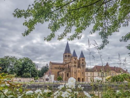 Historic church with towers framed by white flowers and tree branches in Saint Racho, France