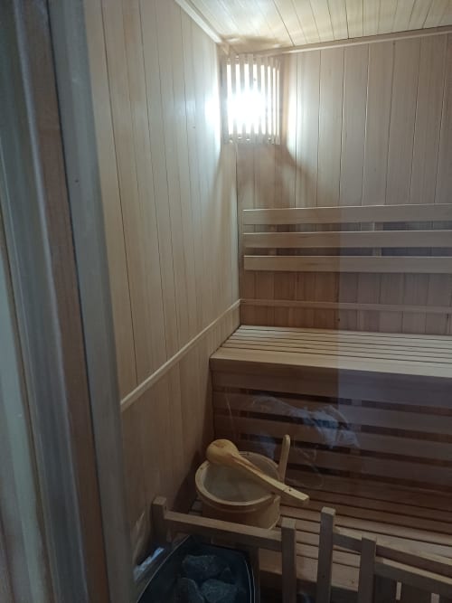 Traditional wooden sauna interior at La Maison de Dun B&B in Saint Racho with benches and ladle