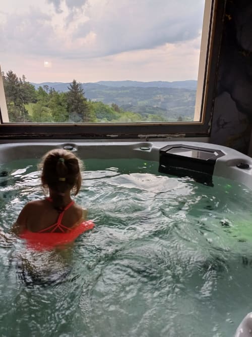 Guest relaxing in hot tub at La Maison de Dun with mountain views of Saint Racho, France