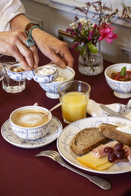 Elegant breakfast table at Castanea Business & Suites in Merelbeke with coffee, pastries, cheese, and fresh flowers