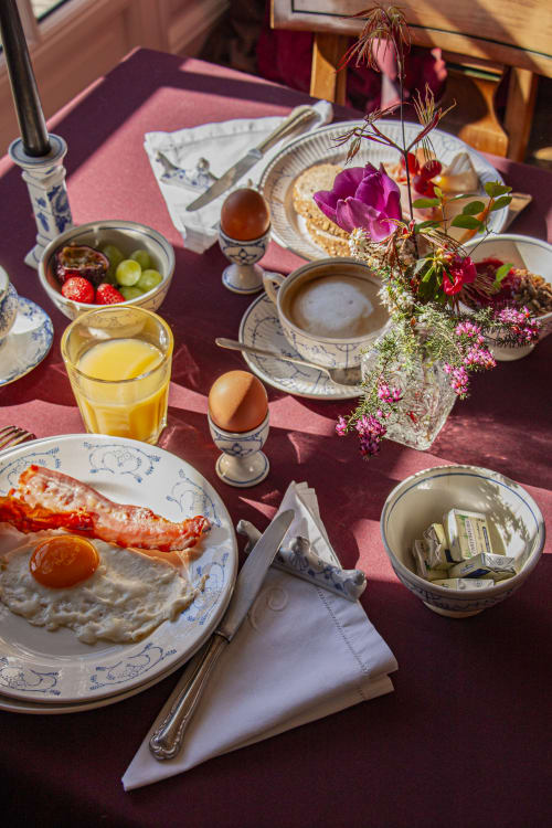 Elegant breakfast table at Castanea with fried egg, bacon, orange juice, coffee, fresh flowers at Merelbeke B&B