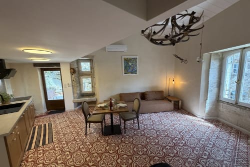 Ferienstudio in „La Sarrasine“ im historischen Herzen von Aiguèze, ausgezeichnet als eines der schönsten Dörfer Frankreichs, nahe den Ardèche-Schluchten, mit fußläufigem Zugang zum Fluss, mit Essecke, braunem Sofa und gemusterten Zementfliesen.