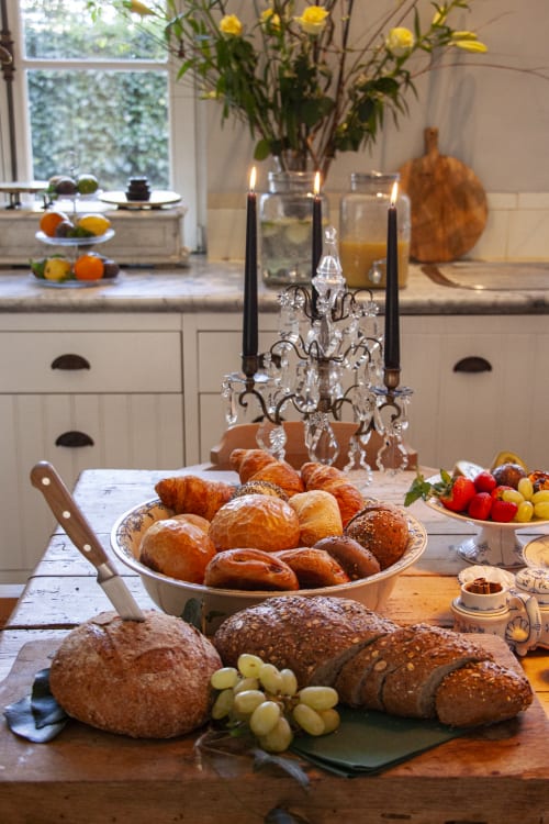 Elegant breakfast spread at Castanea Business & Suites featuring freshly baked breads, pastries, fruits, and crystal