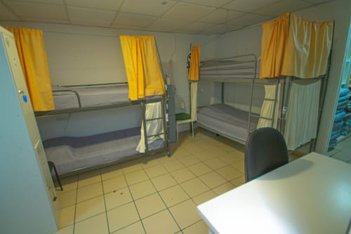Camera dormitorio mista a 4 letti all'Hostel Tropical Work a Las Palmas con letti a castello, tende gialle e pavimenti piastrellati