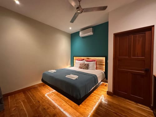 Chambre moderne à l'Organica Yoga Shelter à Paquera avec mur d'accent bleu-vert, lit en bois, parquet, climatisation et plafond