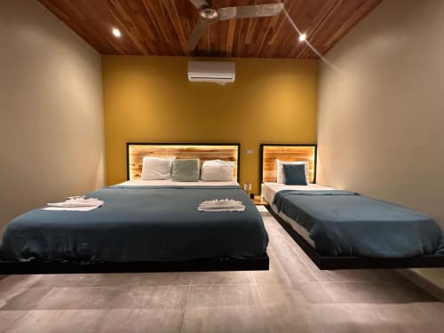 Chambre moderne de l'Organica Yoga Shelter à Paquera avec deux lits, têtes de lit en bois et murs d'accent jaunes