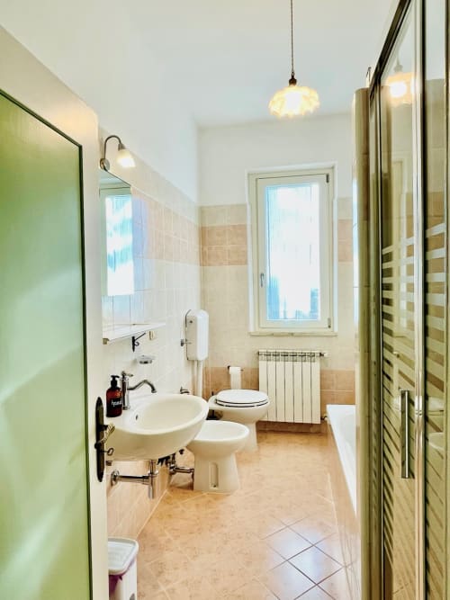 Bagno moderno nell'agriturismo CasaViVa con lavabo, bidet, wc e finestra sulla vista giardino toscano