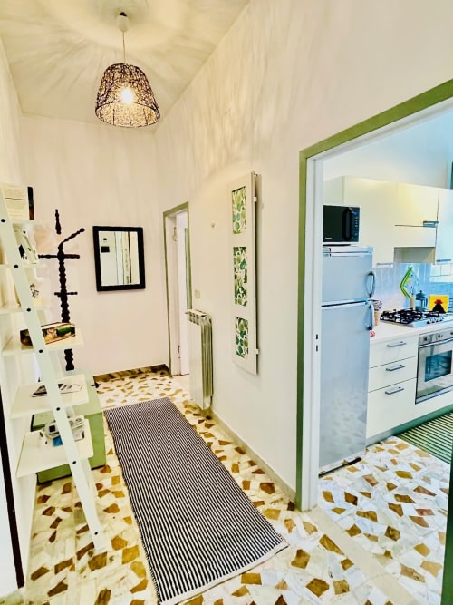 Cucina moderna e corridoio dell'appartamento Agriturismo CasaViVa con pavimenti in piastrelle decorate, finiture verdi e illuminazione a sospensione