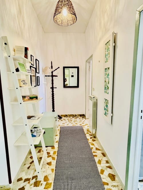 Moderno corridoio dell'Agriturismo CasaViVa con scaffali bianchi, tappeto a strisce e piastrelle geometriche