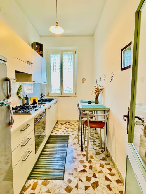 Moderna cucina dell'agriturismo CasaViVa: mobili bianchi, cucina a gas, tavolo da pranzo e pavimento con piastrelle geometriche