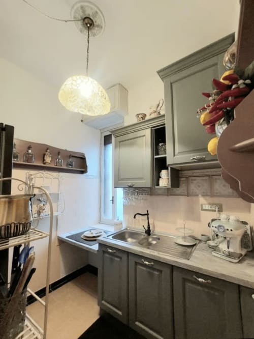 Cuisine moderne grise au Palazzo Losio avec évier en acier inoxydable, luminaires suspendus et couronne décorative à Ponzone
