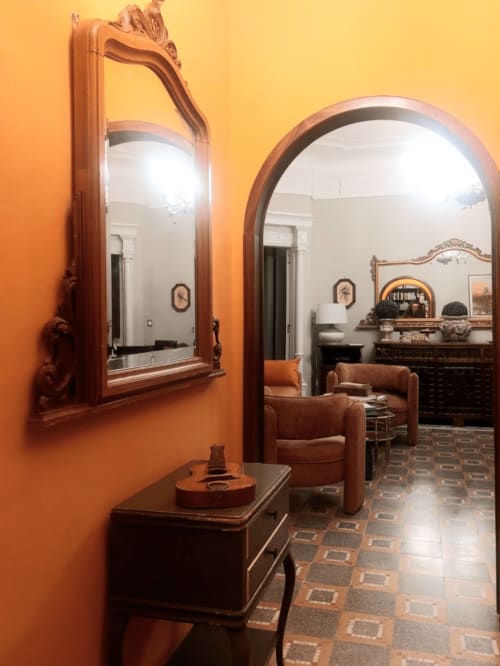 Élégant couloir du Palazzo Losio avec miroirs en bois ouvragé, murs orange et mobilier d'époque à Ponzone