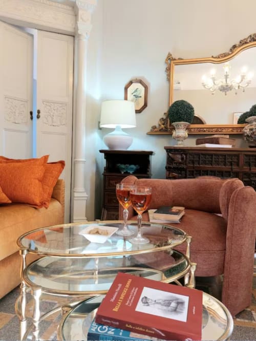 Élégant salon du Palazzo Losio avec canapé orange, table basse en verre, miroir orné et mobilier classique à Ponzone