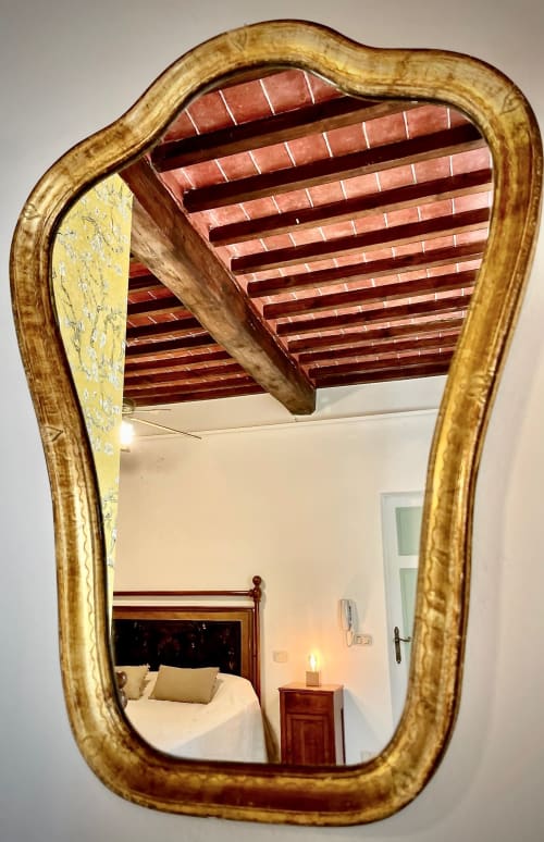 Specchio con cornice dorata che riflette la camera da letto con travi in legno presso Agriturismo CasaViVa, Italia