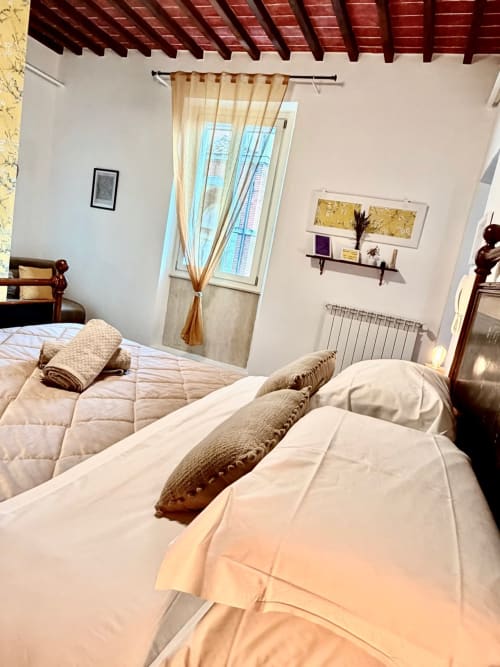 Camera luminosa con letti gemelli, travi in legno e vista su Pozzo della Chiana presso Agriturismo CasaViVa