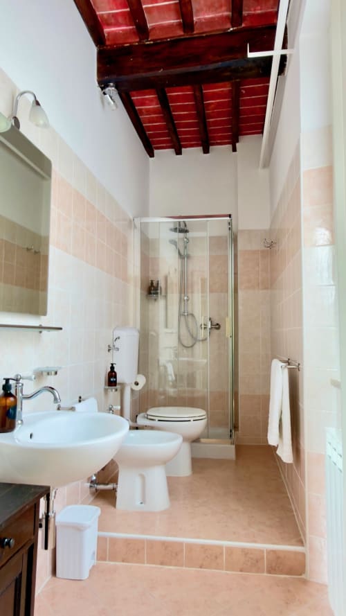 Bagno moderno con doccia, lavabo bianco, toilette, bidet e piastrelle in cotto presso l'Agriturismo CasaViVa in Toscana