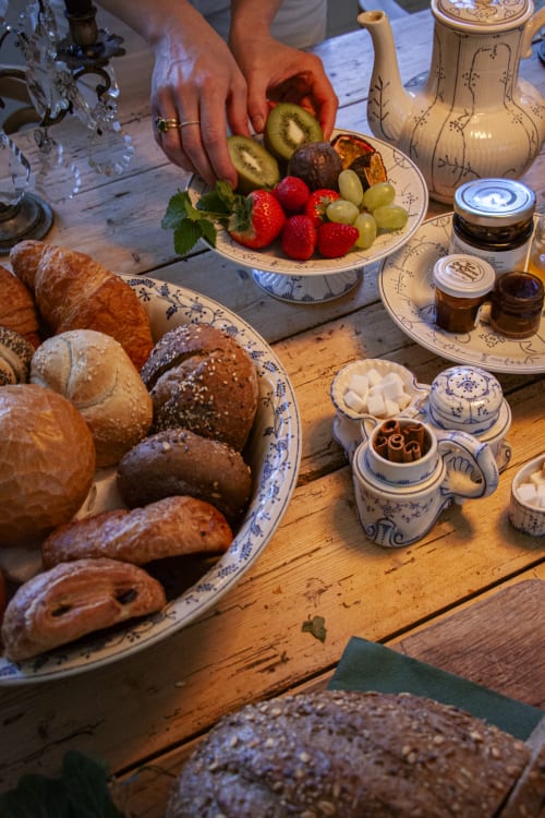 Breakfast spread at Castanea B&B in Merelbeke with fresh fruit, pastries, bread, and spreads on wooden table