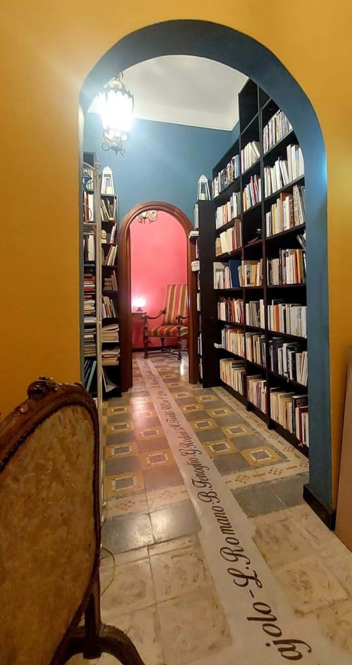 Entrée en arche de la bibliothèque du Palazzo Losio à Ponzone en Italie, avec rayonnages et salle de lecture rouge