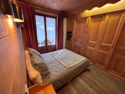 Chambre chaleureuse aux lambris bois chez Francine avec lit queen, rideaux rouges et vue alpine à Notre Dame de Bellecombe