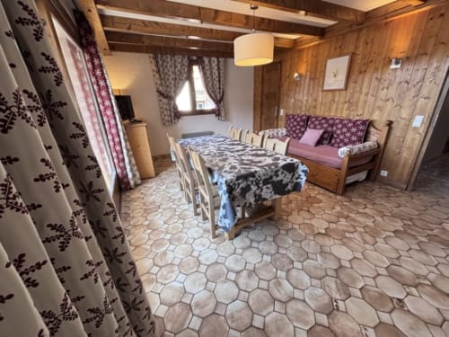Spacieuse chambre alpine chez Francine avec table à manger, canapé, poutres en bois et rideaux à motifs à Notre Dame de