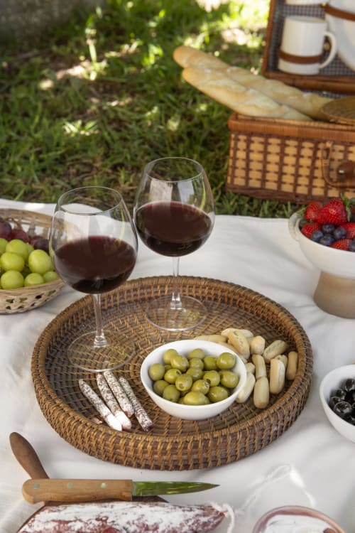 Pique-nique en plein air au Domaine Alga avec vin rouge, olives, charcuterie et fruits rouges frais sur un plateau en osier