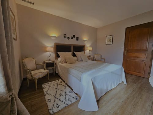 Elegant bedroom at Château de Ribourdin with double bed, wooden furnishings, and garden view lighting in Chevannes, France