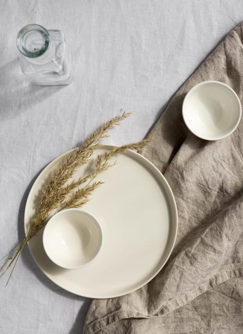 Mise de table minimaliste au Domaine Alga avec vaisselle crème, herbes de la Pampa séchées et verre d'eau sur lin.