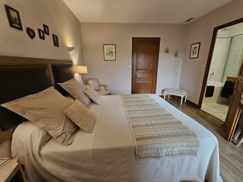 Spacious bedroom at Château de Ribourdin in Chevannes with king bed, dark headboard, ensuite bathroom, and garden views