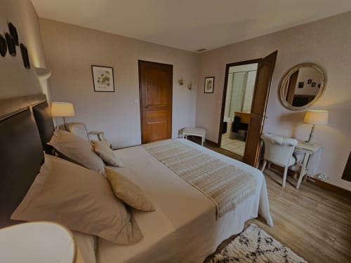 Elegant bedroom at Château de Ribourdin with queen bed, wooden doors, mirror, and garden views in Chevannes France