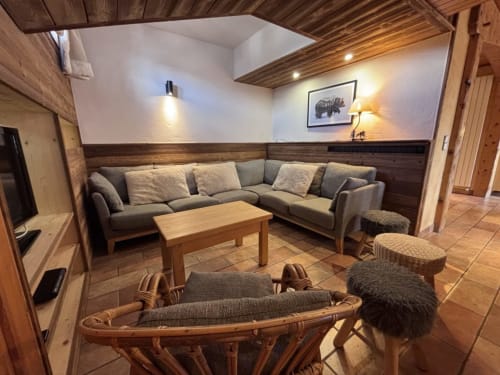 Salon douillet chez Francine avec canapé en L, poutres en bois, cheminée et décor alpin à Notre-Dame-de-Bellecombe
