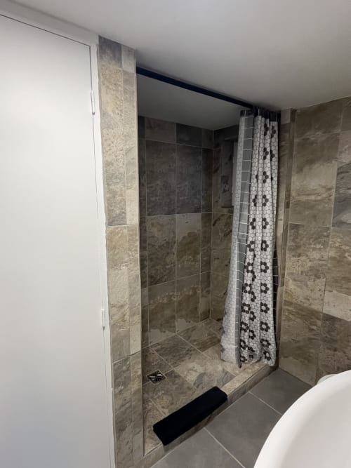 Douche à l'italienne moderne avec carrelage en pierre naturelle et rideau motif à l'appartement Sanateflo à Rai, France