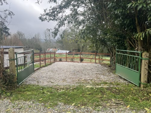 Portail vert ouvrant sur une allée en gravier et jardins de ferme à l'appartement Sanateflo, Rai France