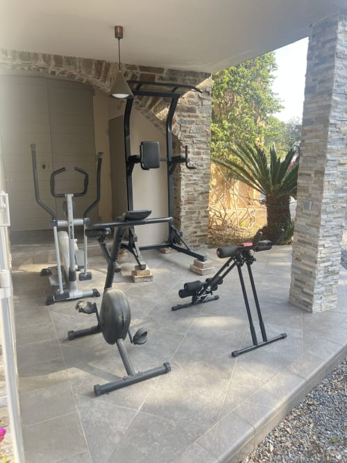 Outdoor fitness area at Villa Nais with stationary bike and exercise equipment on covered patio, Bormes les Mimosas