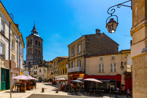 Place historique de Bourg-Charente avec terrasse de café, clocher et architecture française charmante