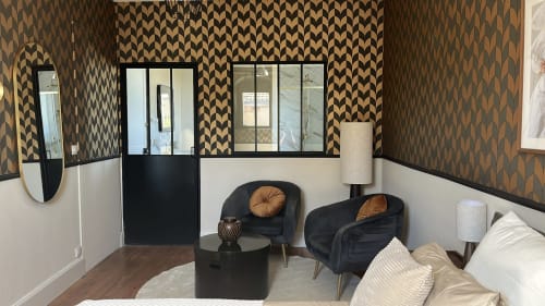 Suite Signature élégante à La Poterne avec papier peint géométrique, fauteuils noirs, mobilier contemporain et vue sur le jardin