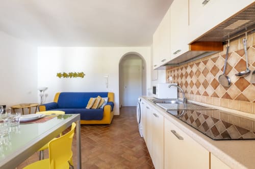 Modern kitchen and living area in Youinsardinia apartment, Bari Sardo, with blue sofa, yellow accents, tiled backsplash