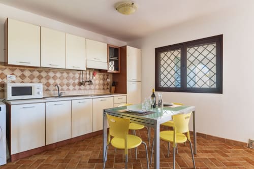 Modern kitchen and dining area in Bilocale Veranda Large apartment, Bari Sardo, with cream cabinets, terracotta tile