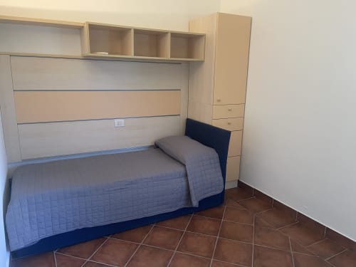 Modern bedroom at Like at Home Palau with bed, built-in storage, and terracotta tile flooring in Palau, Italy