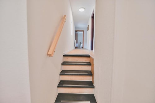 Escalier aux marches en bois et contremarches noires menant à l'étage dans l'appartement Le Petit Havre de Joy, Dambach la Ville, France